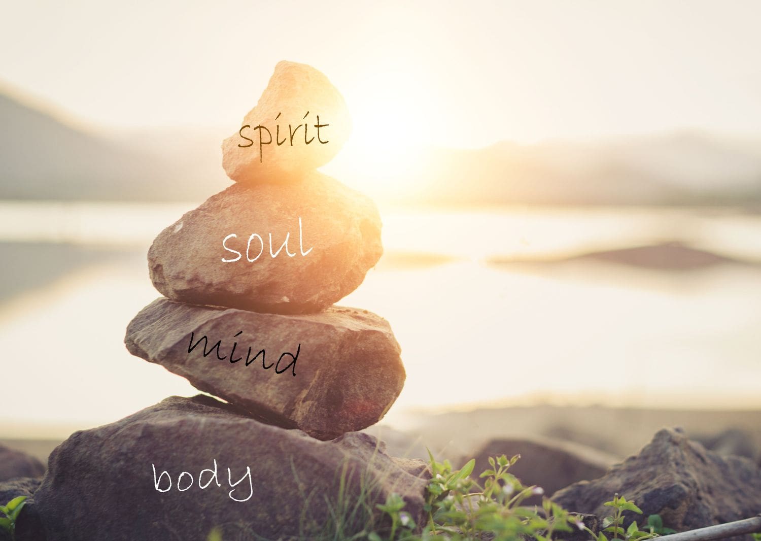 A stack of rocks with the words " spirit, soul, mind ," body and soul written on them.