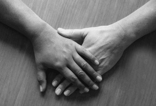 Two hands are holding each other on a table.
