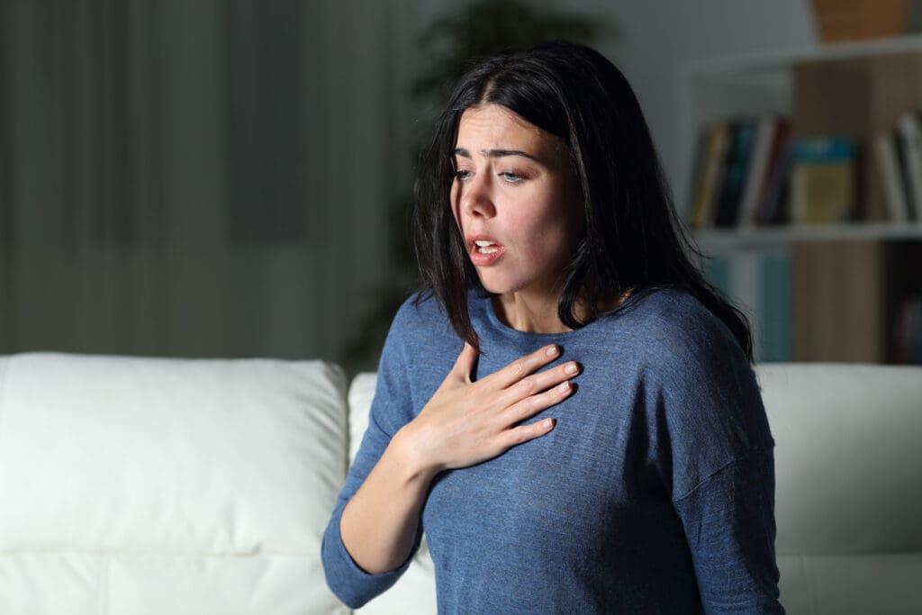 Young woman experiencing chest discomfort indoors.