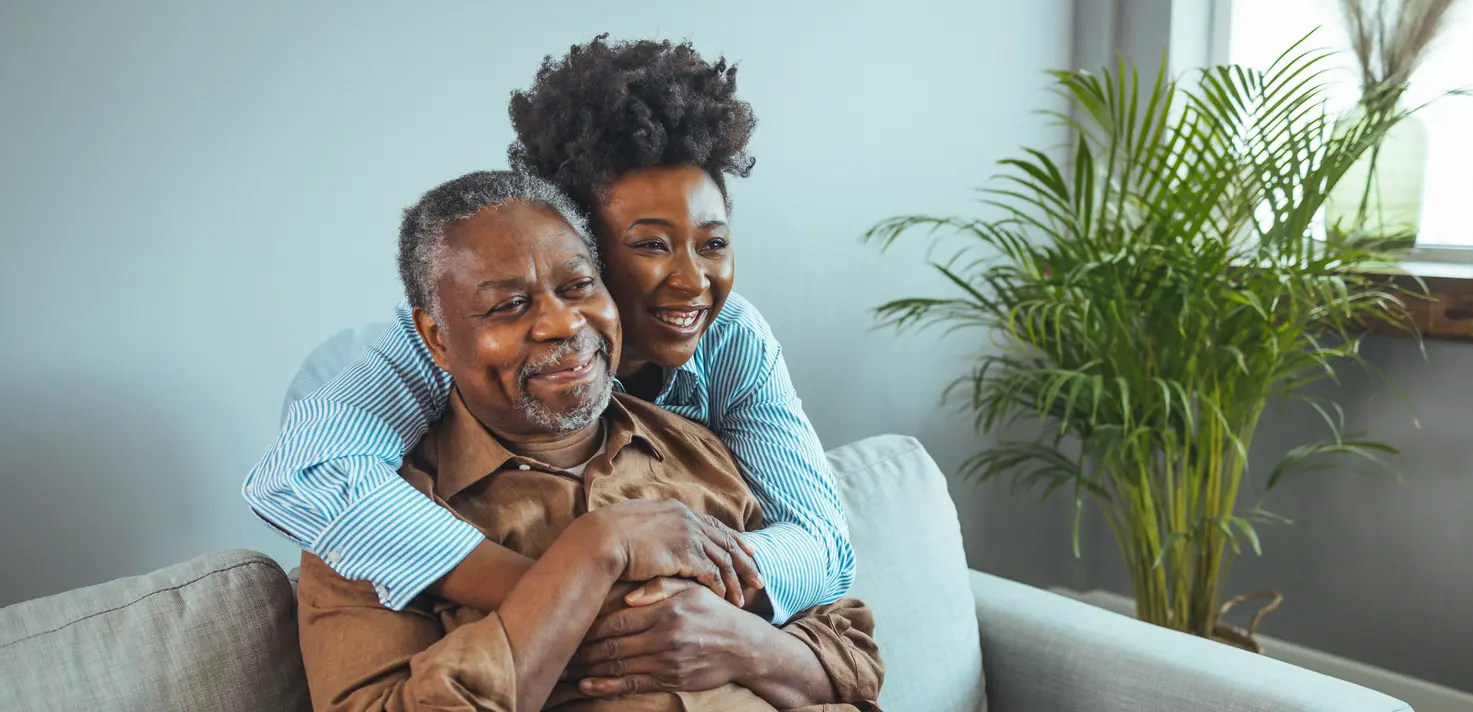 Happy couple embracing and smiling on a couch.